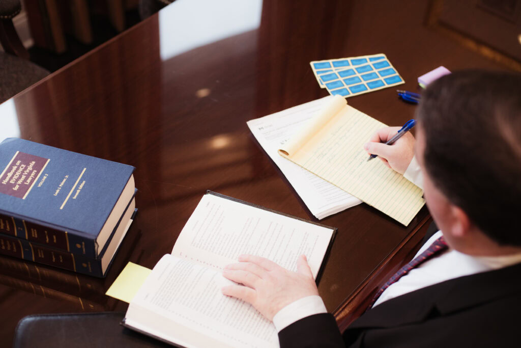 Criminal defense attorney reviewing case materials and taking notes while preparing for trial in West Virginia.